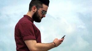Man looking at phone to see when does persistence become harassment or stalking